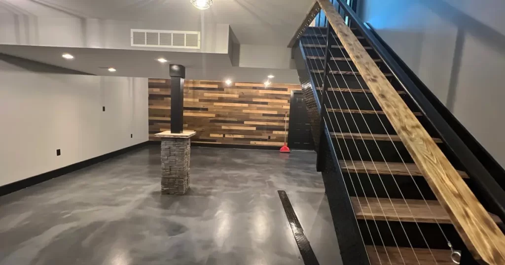 Finished basement with polished concrete floors, modern cable railing stairs, and reclaimed wood accent wall - featured