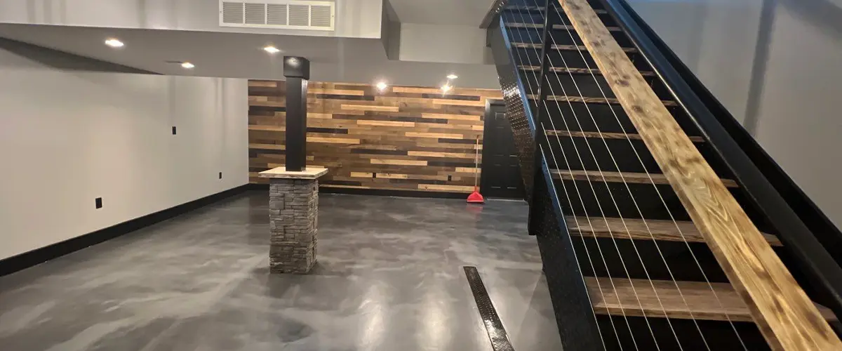 Finished basement with polished concrete floors, modern cable railing stairs, and reclaimed wood accent wall.