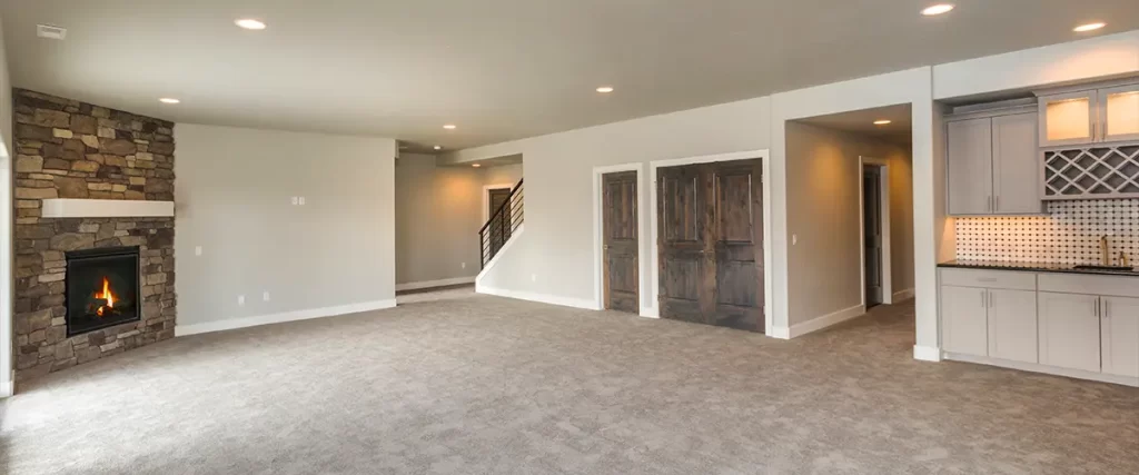 Spacious finished basement with carpet flooring, stone fireplace, and built-in wet bar with wine rack.