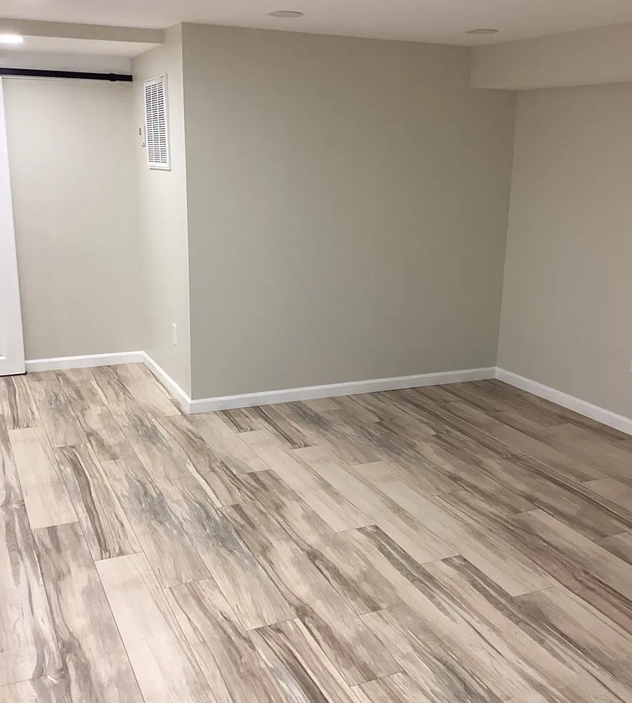 Basement room with light wood-look tile flooring and neutral walls