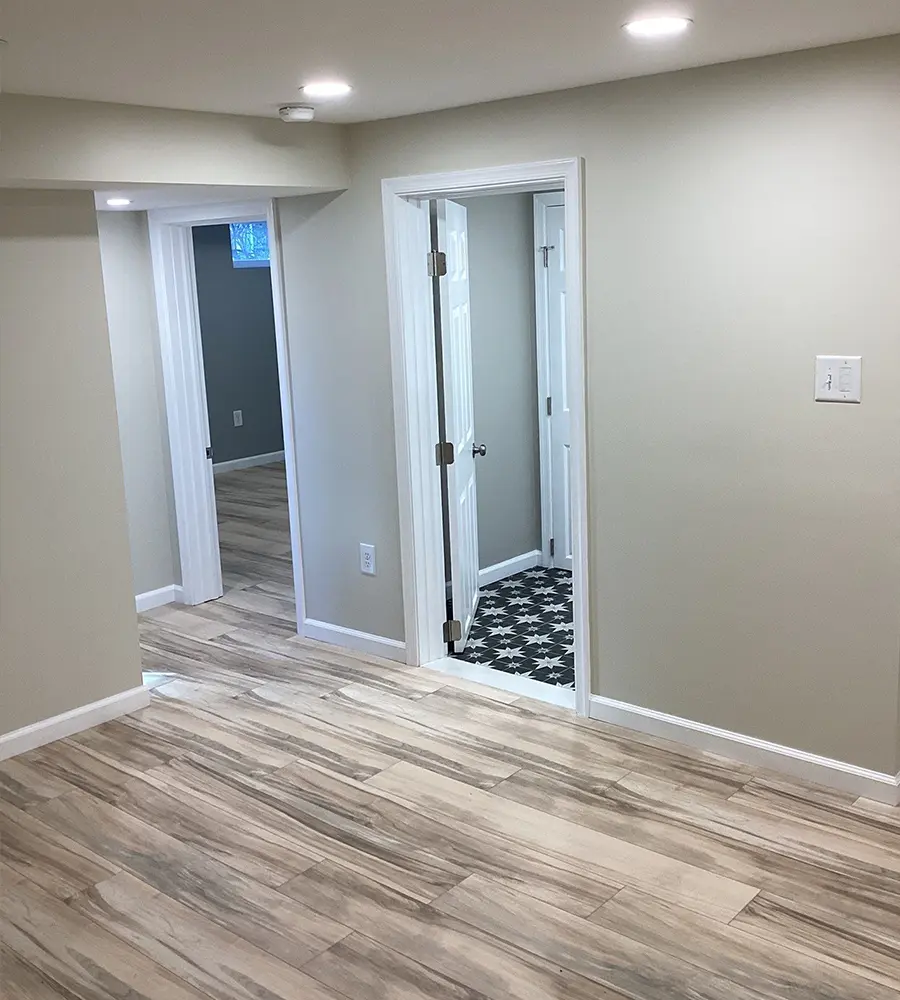 Basement hallway with wood-look tile flooring and open doorways