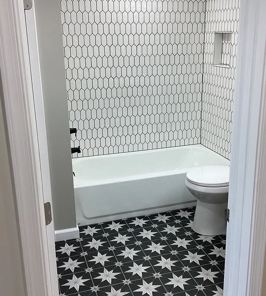 Modern bathroom with patterned tile floor and white tub surround
