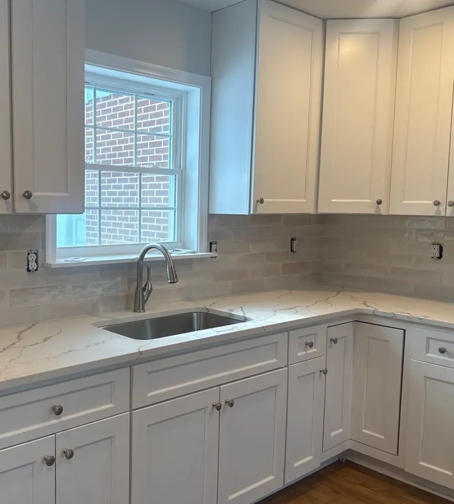 White shaker cabinets and quartz countertops with tiled backsplash