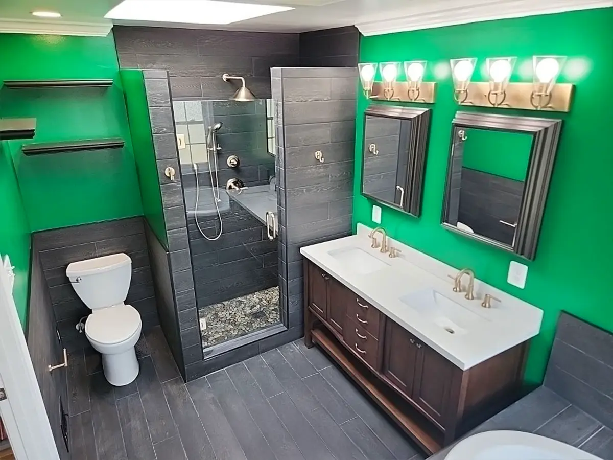 Bold bathroom with green walls, dark tile, and dual vanity sinks