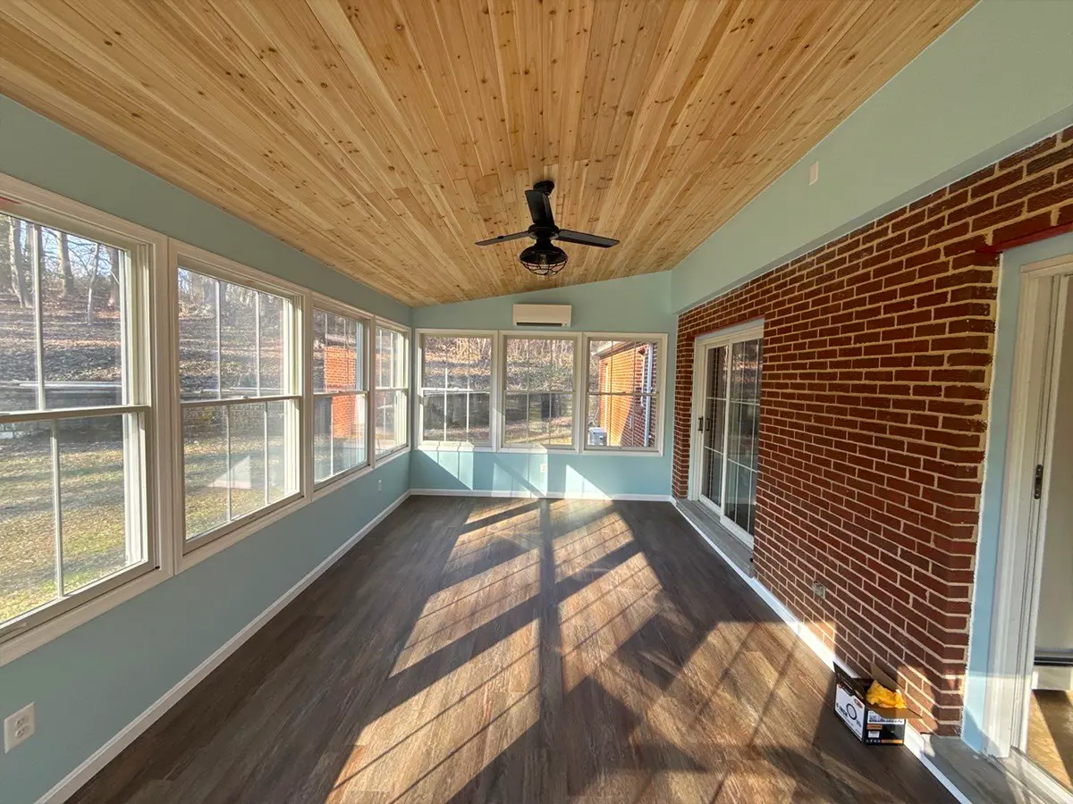 Finished sunroom addition with brick wall, large windows, and wood ceiling