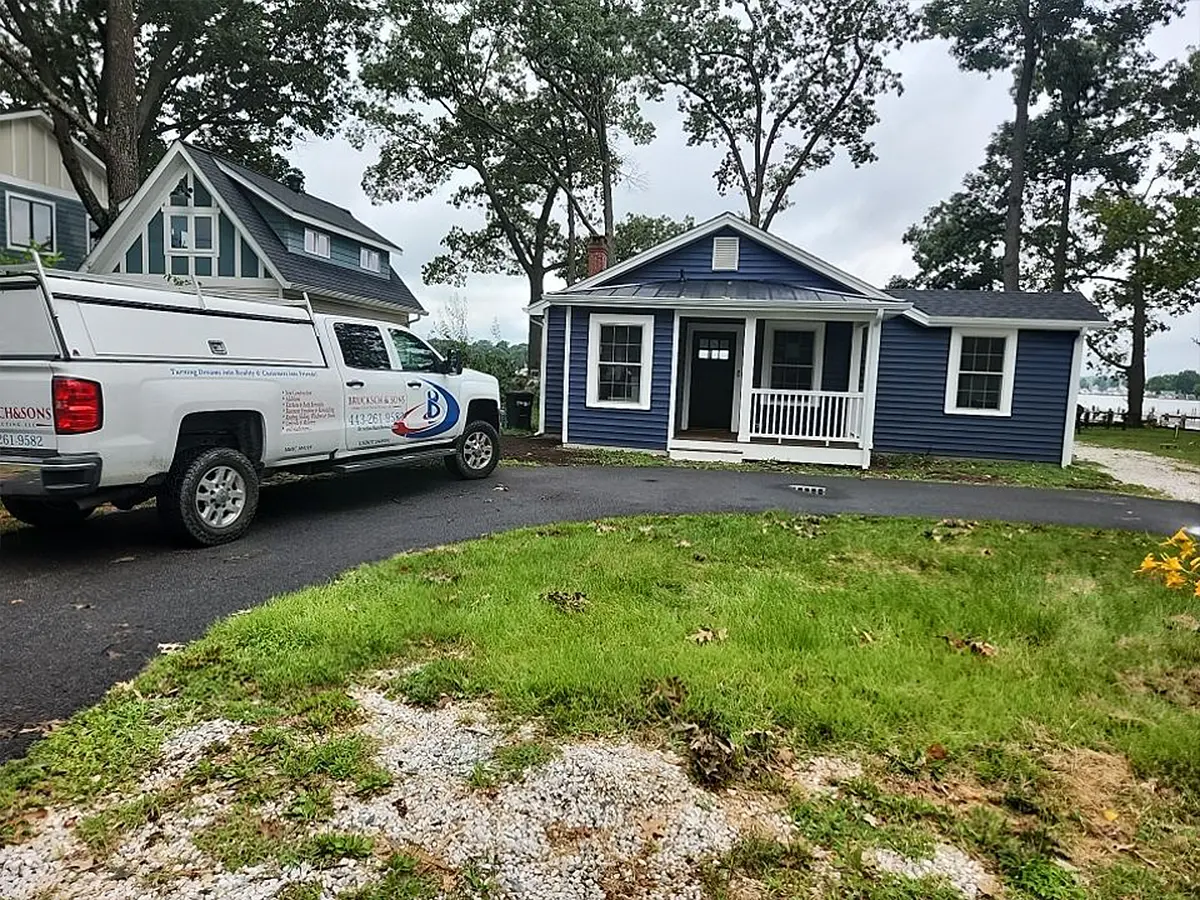 Blue siding home with front porch and Brucksch & Sons service truck parked in driveway