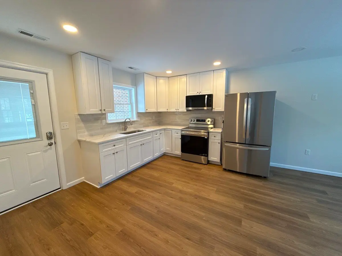 Modern white kitchen with stainless steel appliances and wood-look flooring