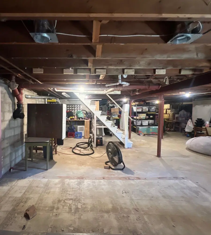 Unfinished basement with cluttered storage and exposed ceiling
