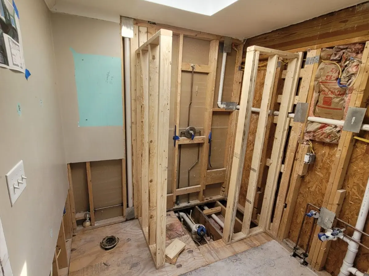 Exposed framing in bathroom under renovation with visible plumbing