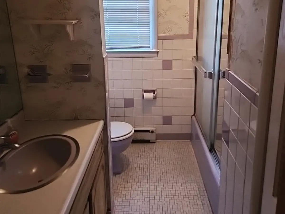 Outdated small bathroom with tile walls and enclosed tub-shower combo