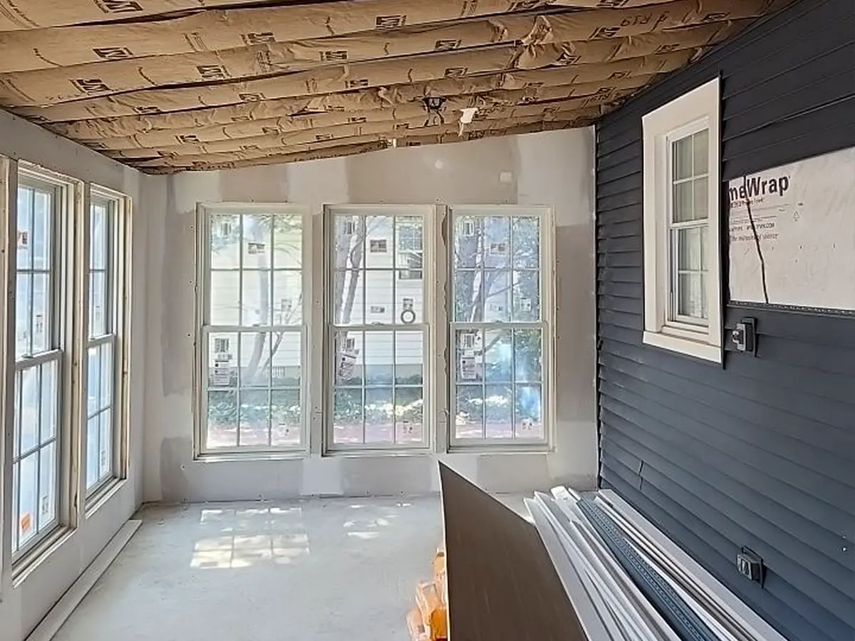 Insulated sunroom under construction with white drywall and dark siding