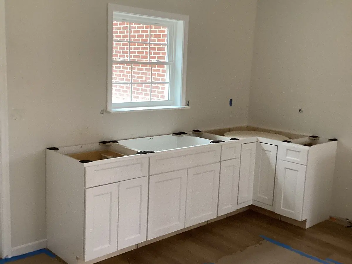 White base cabinets partially installed in an unfinished kitchen space