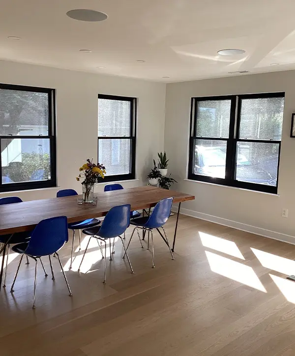 Bright dining room with wood table, blue chairs, and large black-trim windows for a modern minimalist look