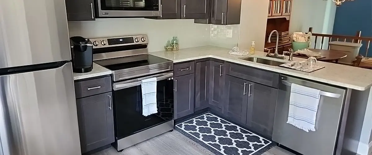 Modern L-shaped kitchen with dark cabinets, stainless steel appliances, and light countertops for small spaces