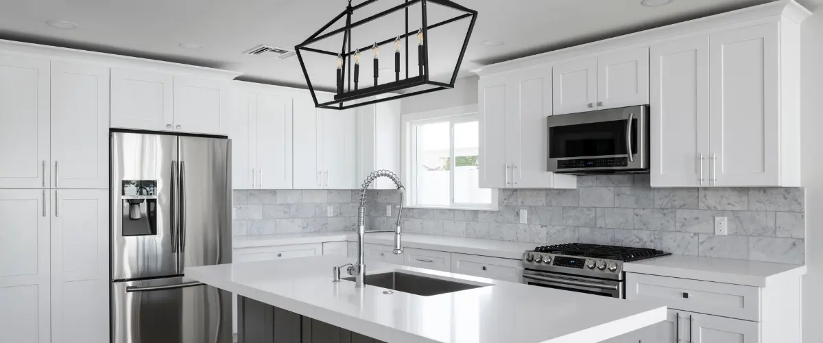 Bright white kitchen with island, marble backsplash, and stainless steel appliances.