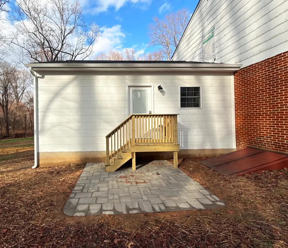 Small home addition with white siding and a wooden entry staircase