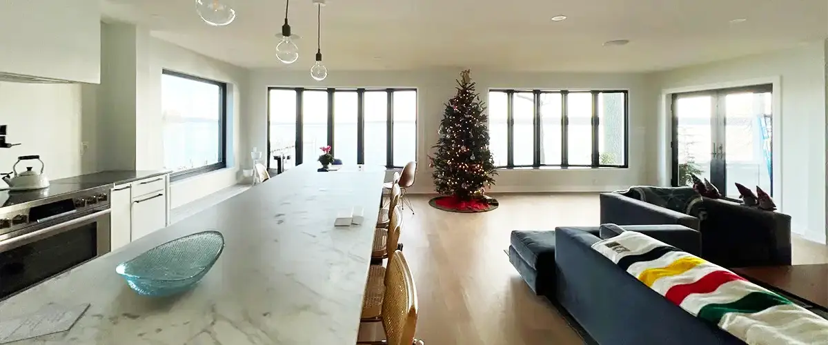 Open concept kitchen and living room with Christmas tree and large windows