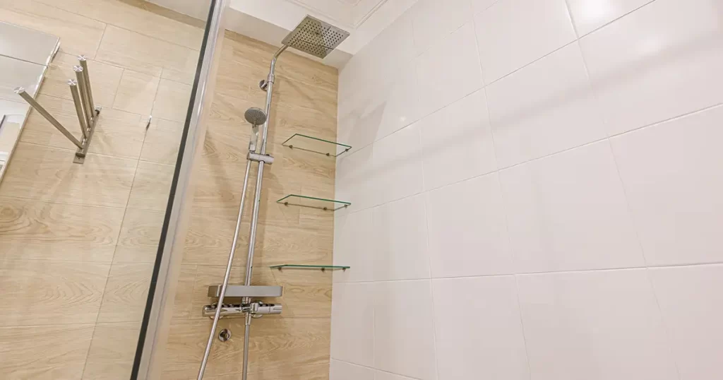 Shower with glass corner shelves and wood tile wall