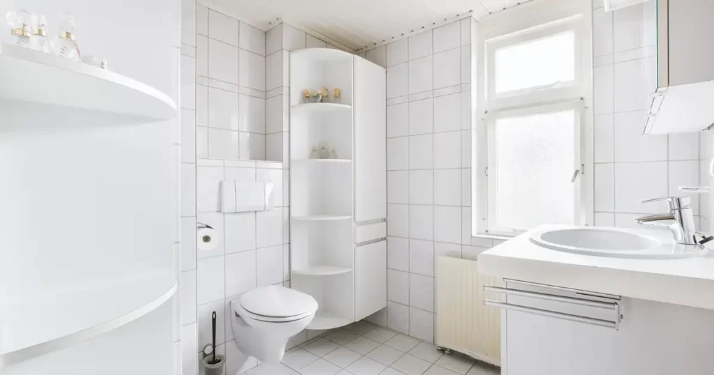 White tiled bathroom with built-in corner shelving unit