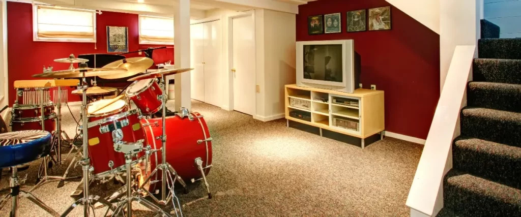 A red basement featuring a drum set and a carpet flooring
