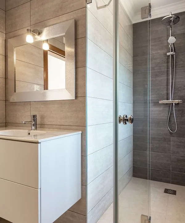 A modern bathroom featuring a glass-enclosed walk-in shower with grey tiles and a sleek white vanity, installed by bathroom remodeling contractors in Arnold, MD.
