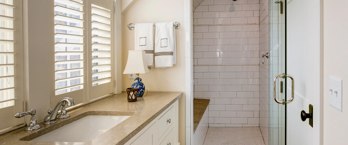 A luxury home showcasing bathroom accessibility for seniors with a walk-in subway tile shower, a built-in stone sitting bench, and high-contrast grab handles for safety.