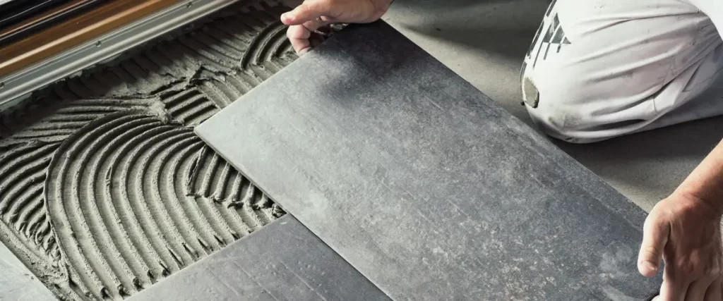 A professional contractor installing bathroom features and hardware on a tiled wall.