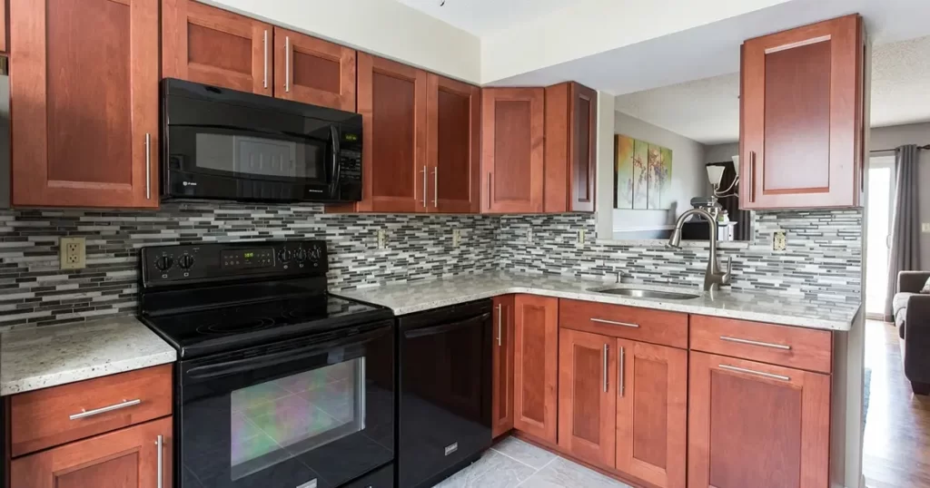 L-shaped kitchen layout with stove, corner sink, and upper cabinets