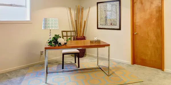 Basement office setup with carpet, wooden desk, and wall art in a cozy, low-ceiling home workspace Basement office setup with carpet, wooden desk, and wall art in a cozy, low-ceiling home workspace